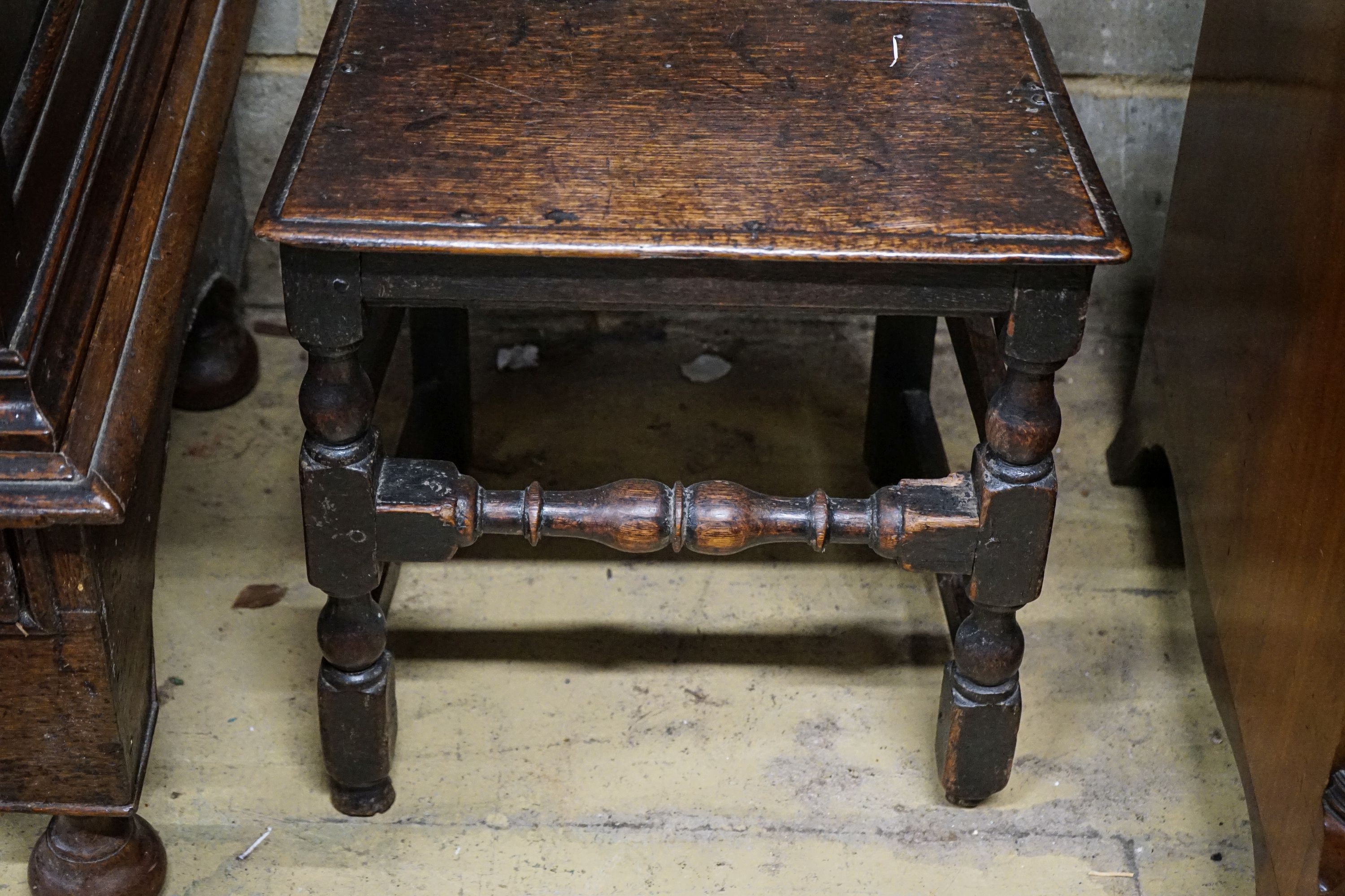 A late 17th century oak back stool, with carved cresting rail, slatted back and solid seat, on turned and square underframe, width 45cm, height 107cm